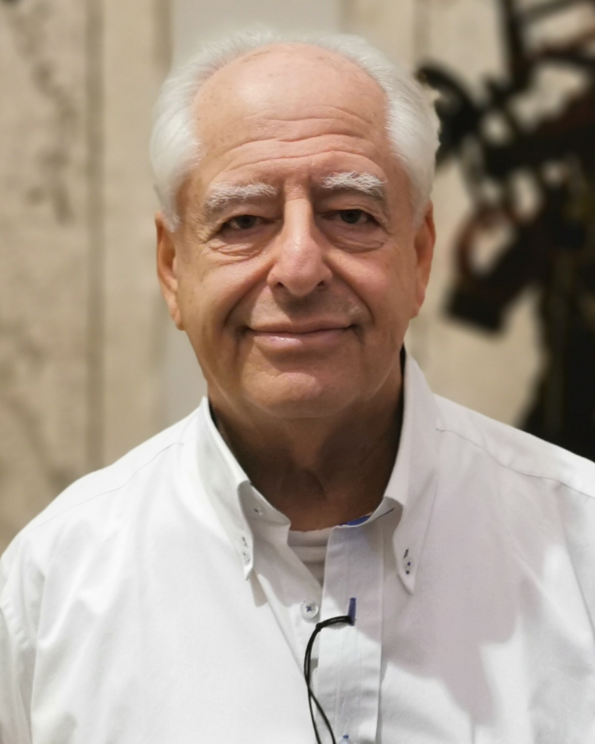 William Kentridge, white-haired, in an open-necked white shirt, smiling at the camera