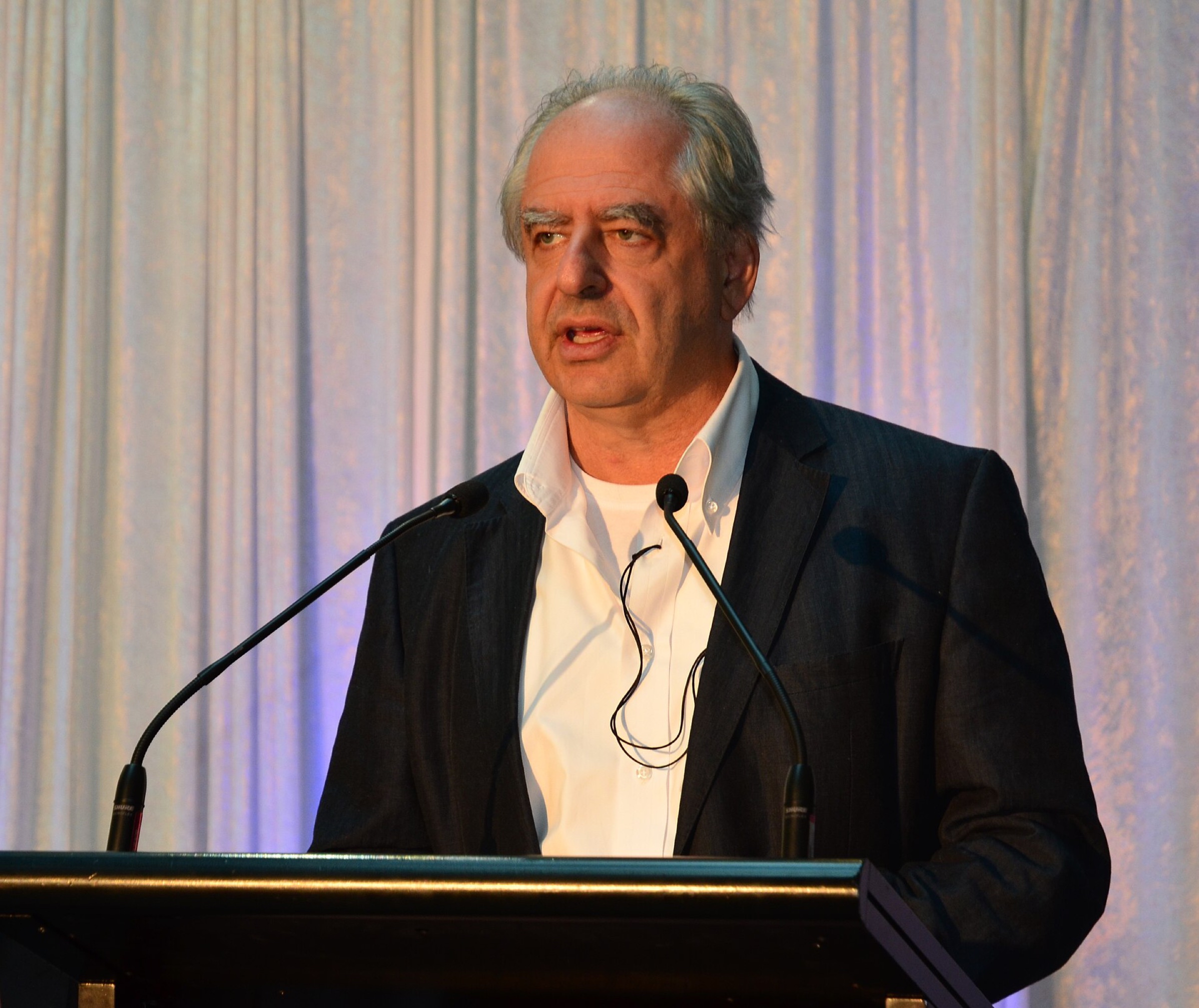 William Kentridge speaking at a lectern at an exhibition opening in Melbourne