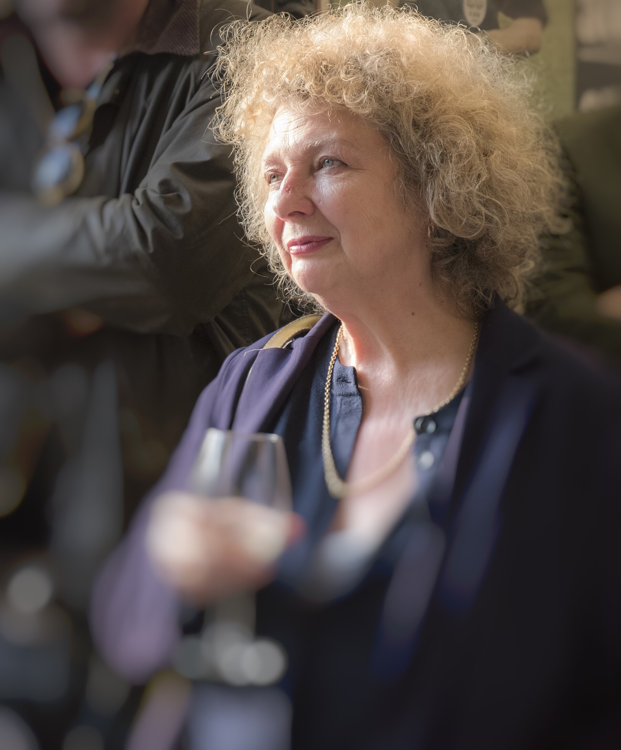 Marlene Dumas at an exhibition opening in The Hague in 2018, looking to one side, with a glass in her hand