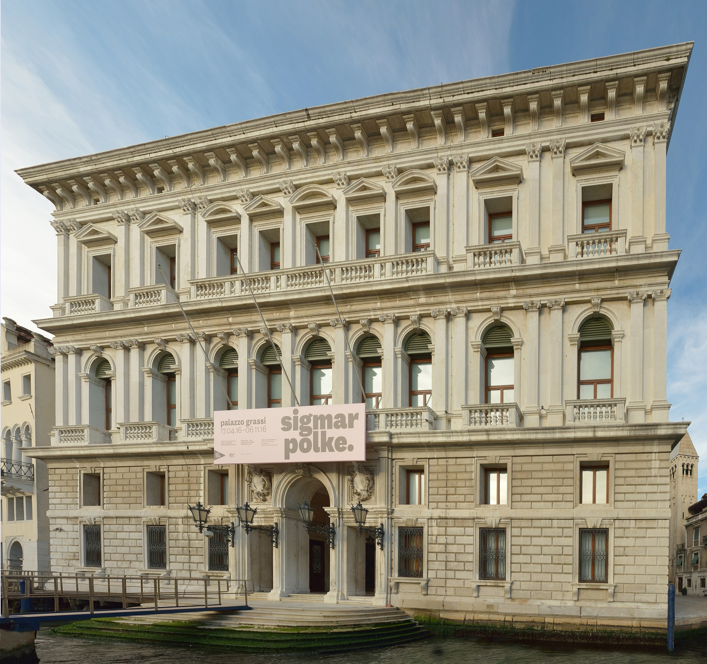 The white stone façade of Palazzo Grassi on the Grand Canal in Venice, with a landing stage in front