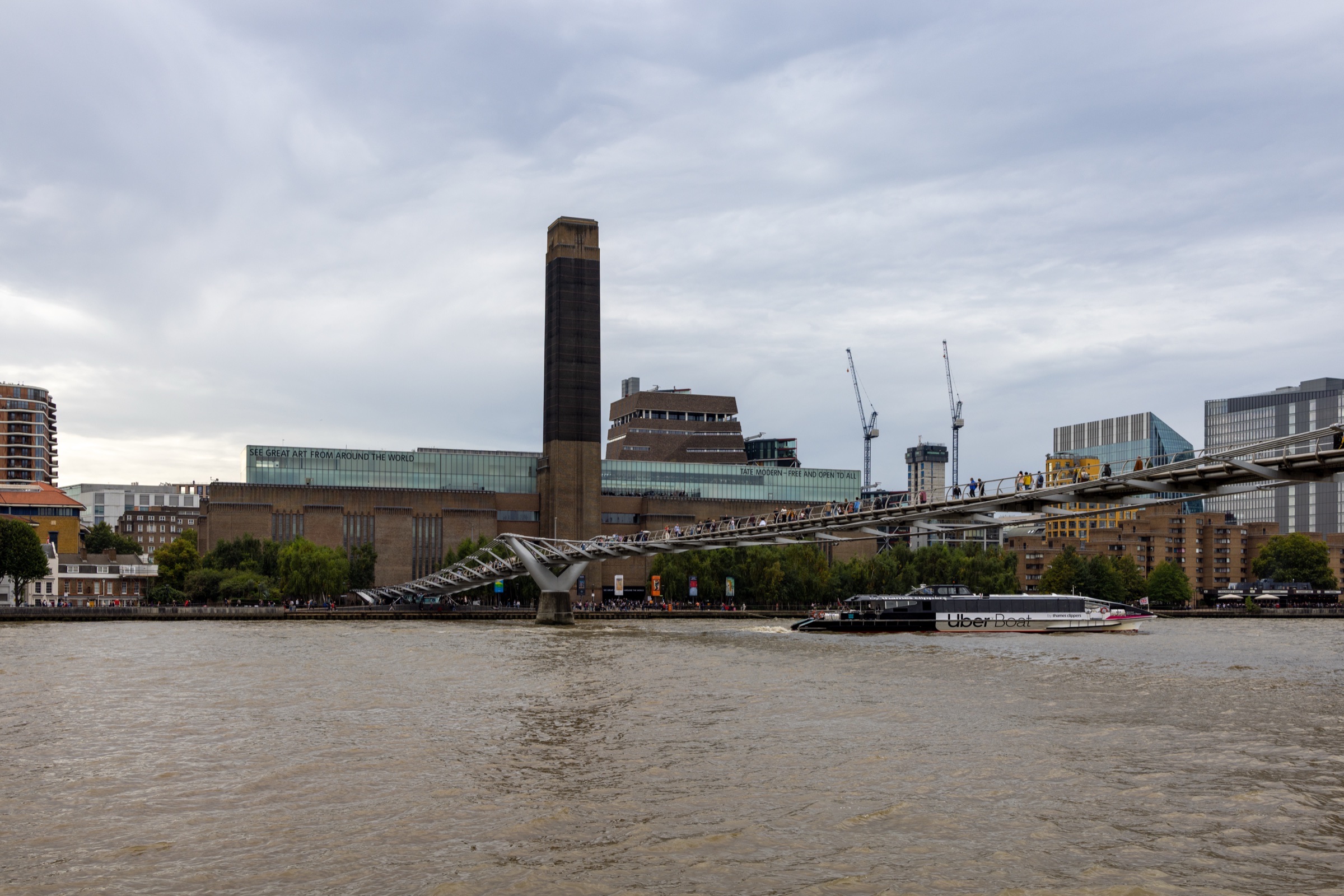 Tate Modern and its chimney seen from the Thames, with the Millennium Bridge in front