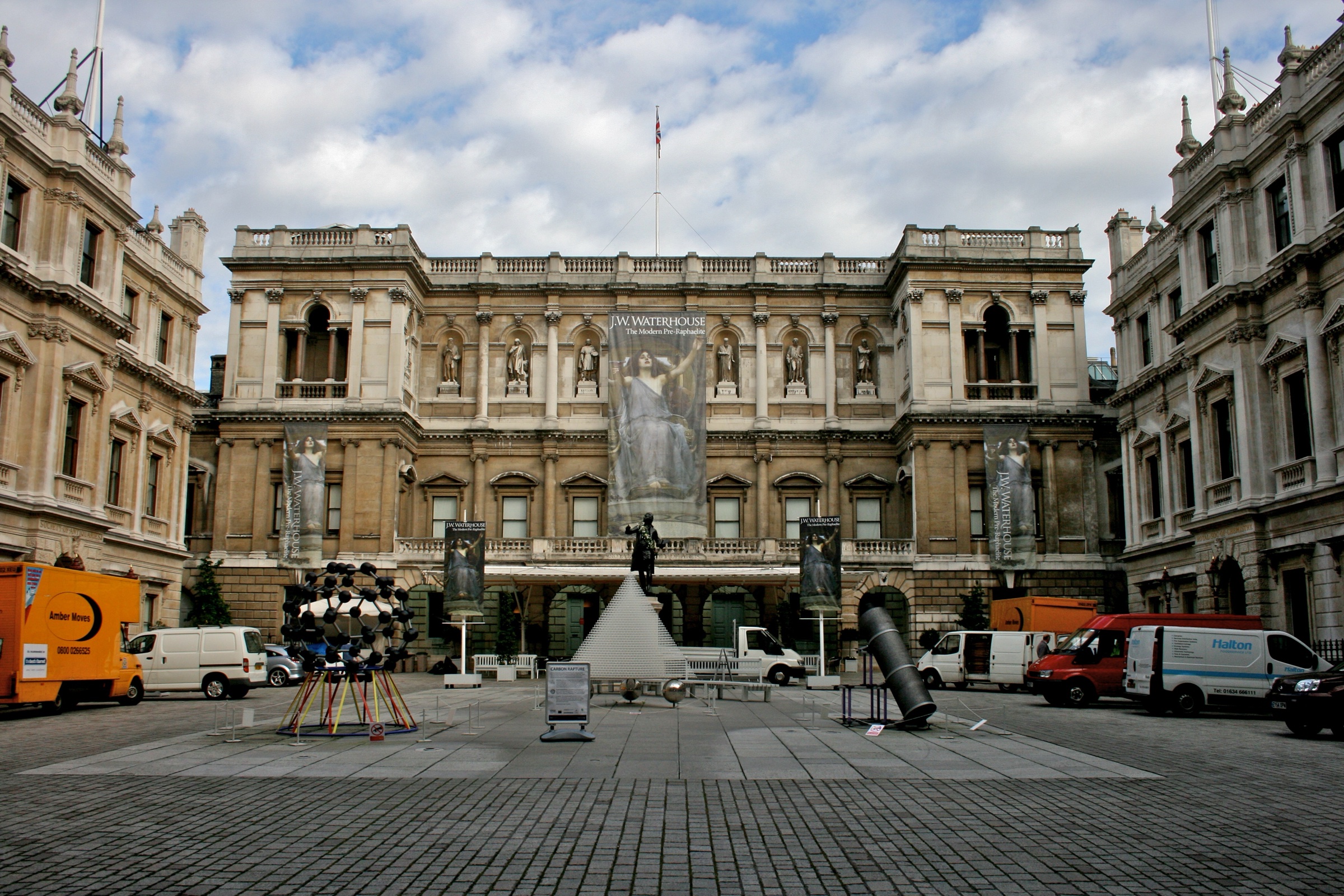 Burlington House on Piccadilly, home of the Royal Academy of Arts, seen across its cobbled courtyard under a cloudy sky