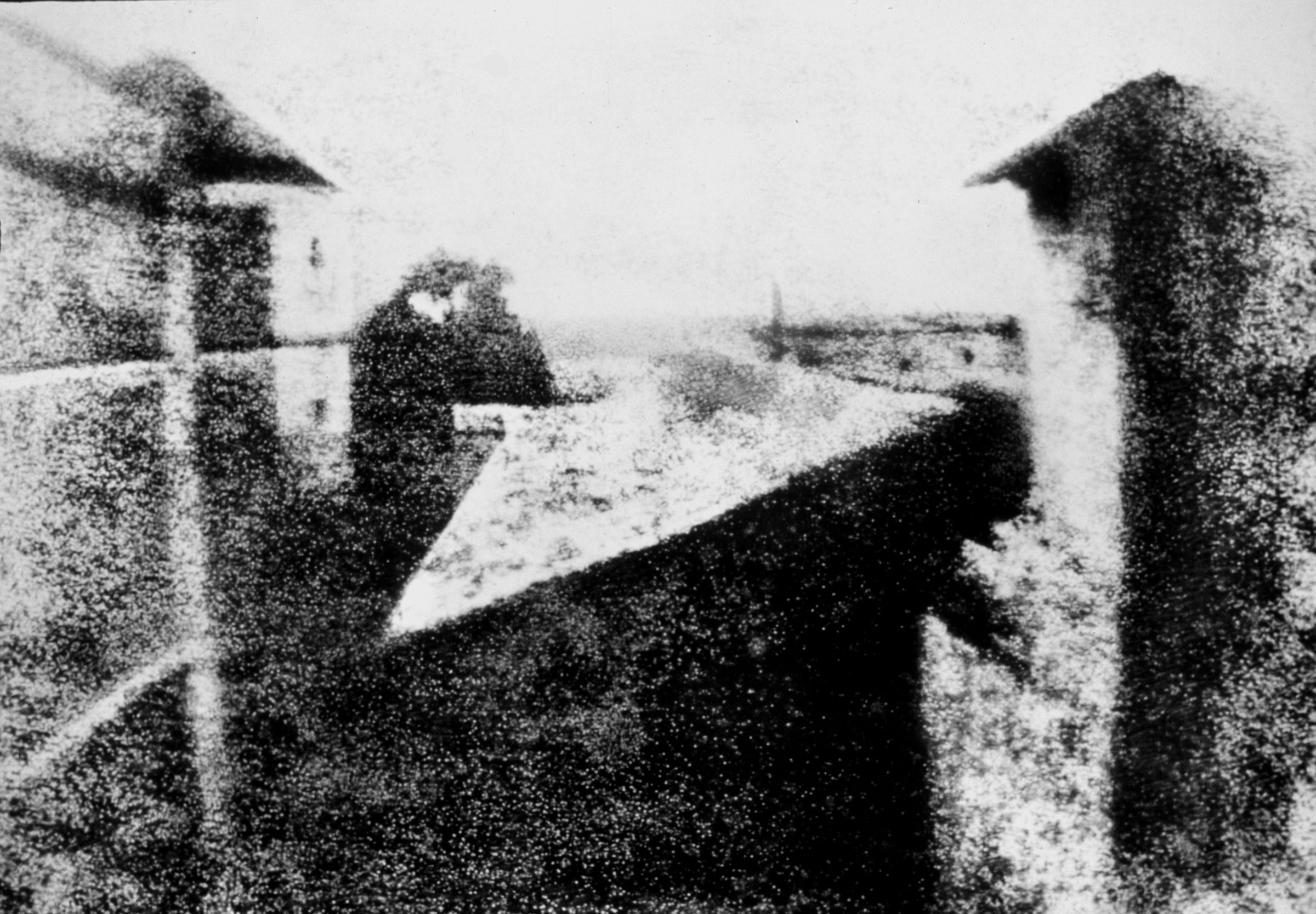 A grainy grey image of rooftops and a courtyard seen from a high window, the earliest surviving photograph