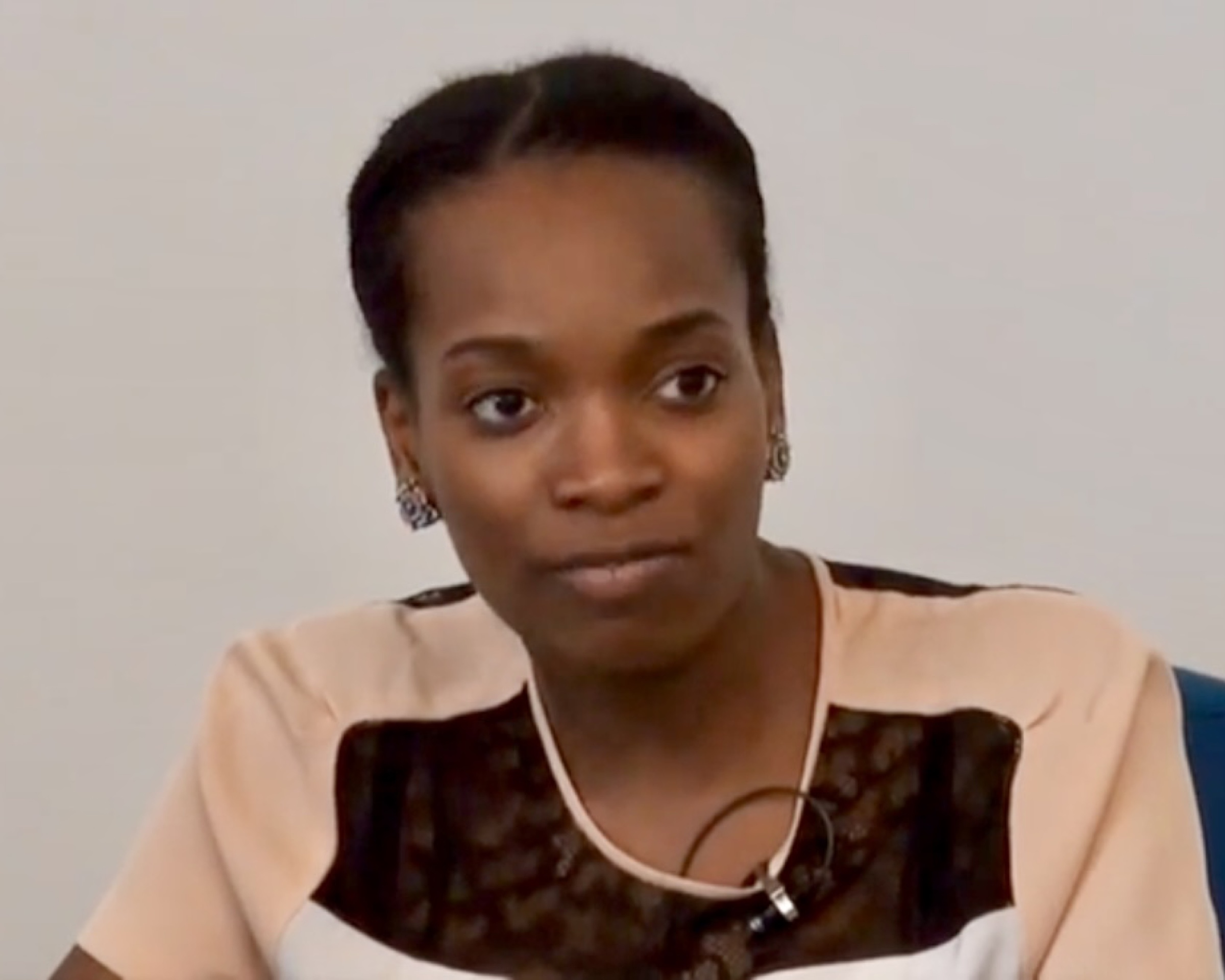 Njideka Akunyili Crosby in a pale top with a dark collar, listening during an interview