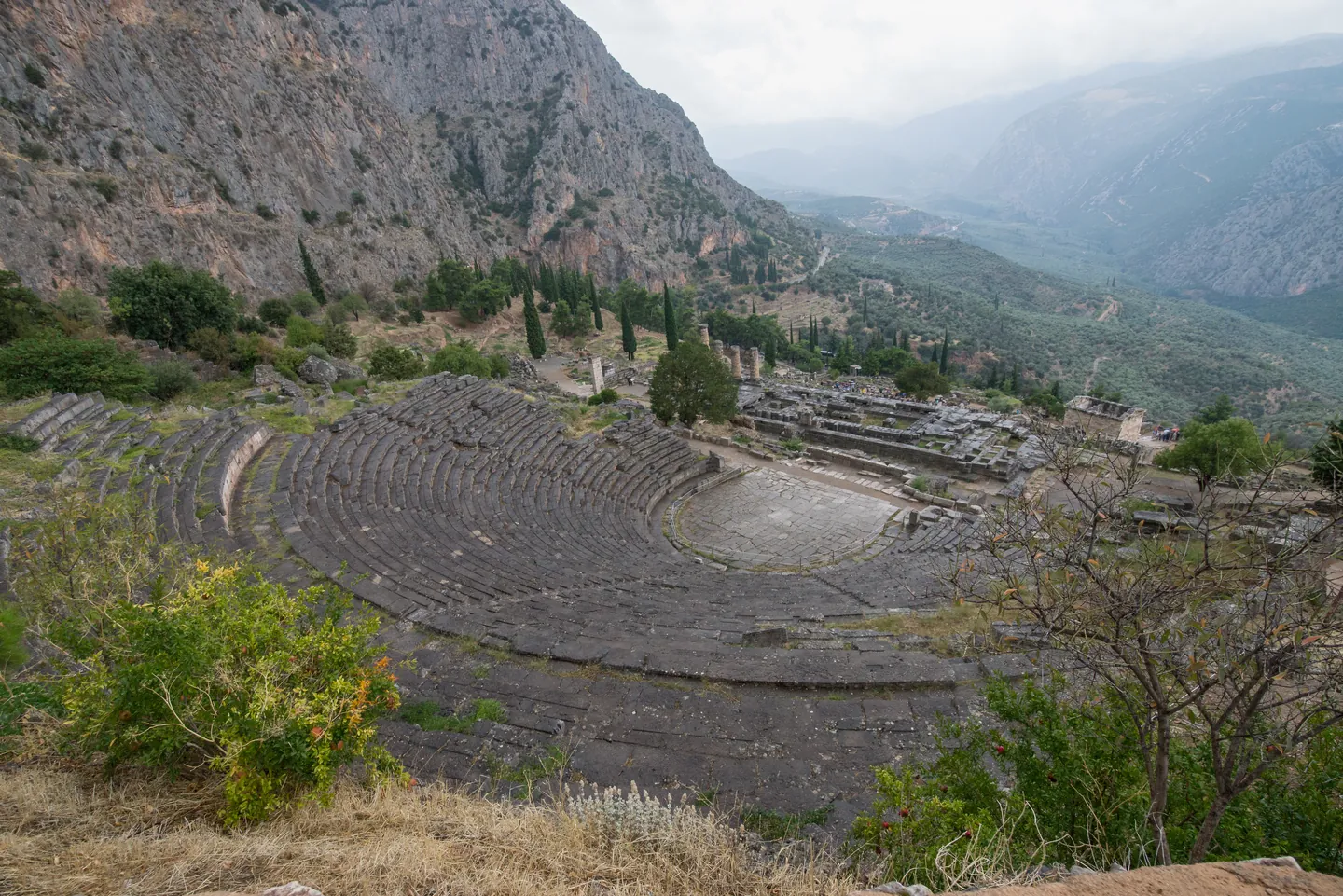 The ancient theatre at Delphi seen from above, with the Temple of Apollo below and the mountains and valley beyond