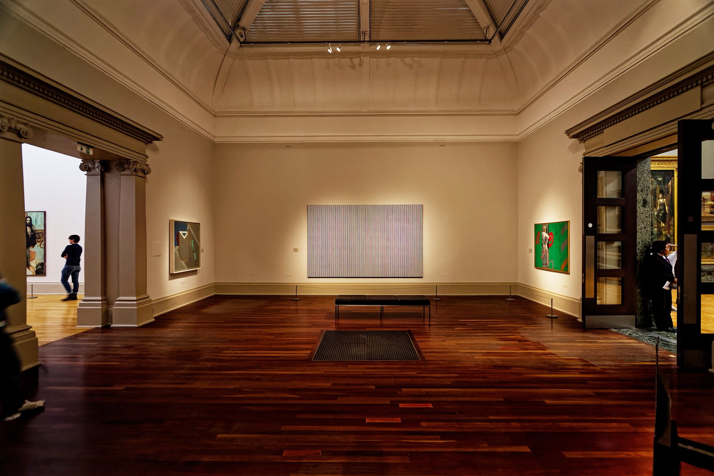 A gallery at Tate Britain with Bridget Riley's pale striped painting Late Morning on the far wall