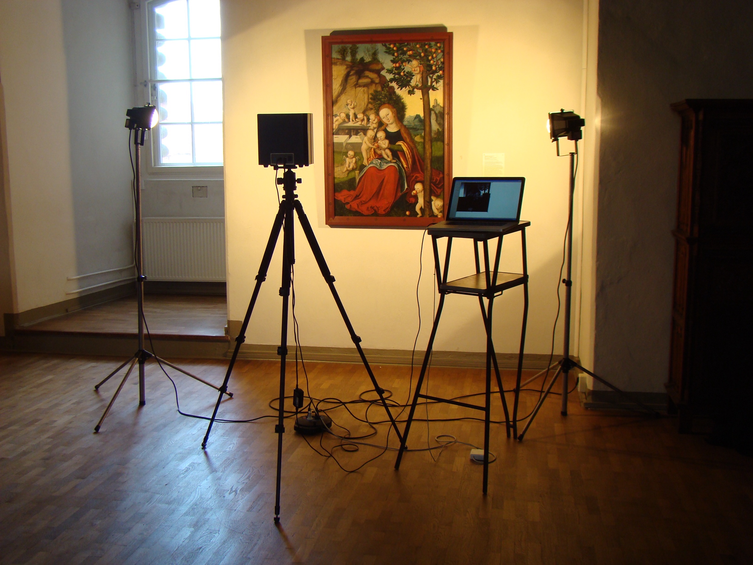An infrared camera on a tripod in front of a Cranach Madonna, used to see the drawing beneath the paint